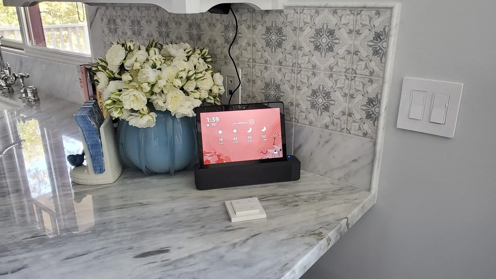 A tablet is sitting on a counter next to a vase of flowers.