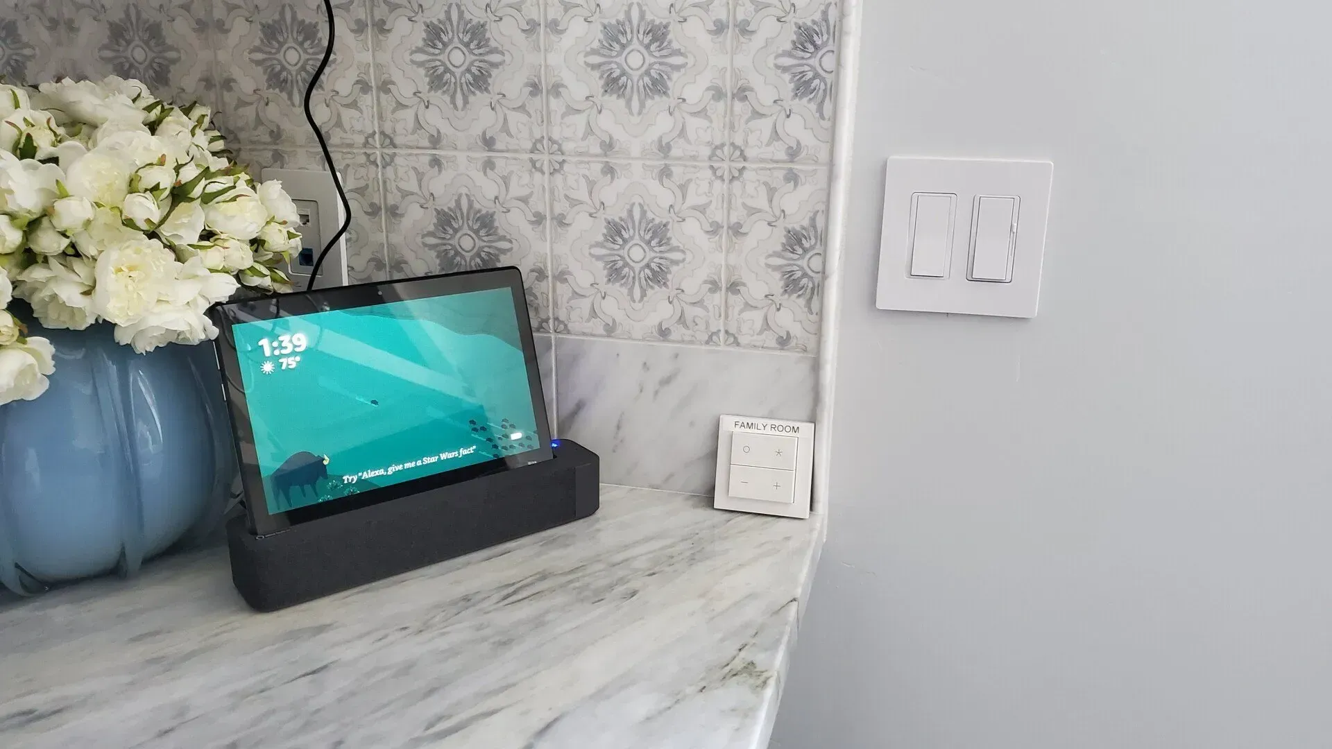 A tablet is sitting on top of a counter next to a vase of flowers.
