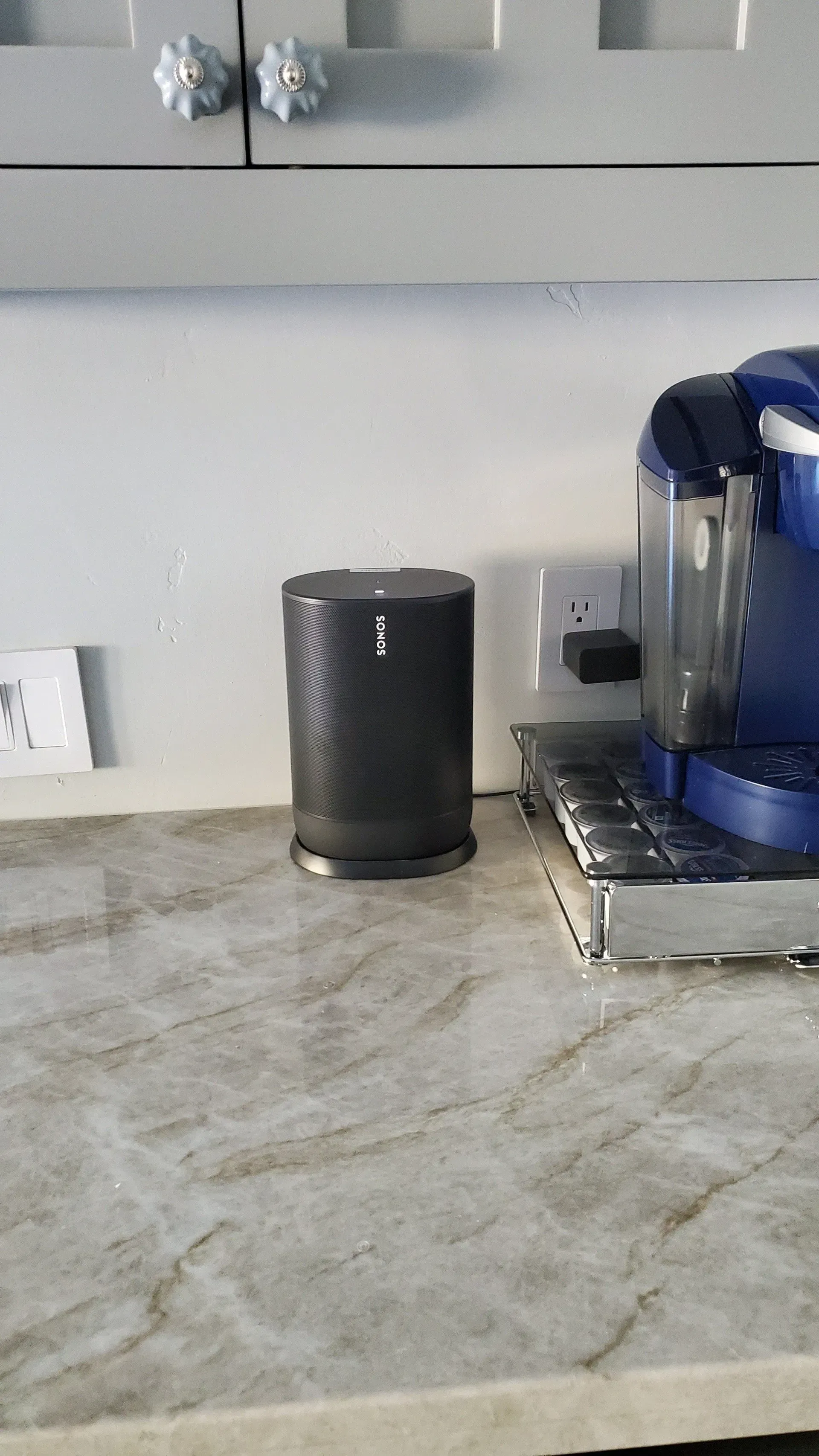 A kitchen counter with a speaker and a coffee maker on it.