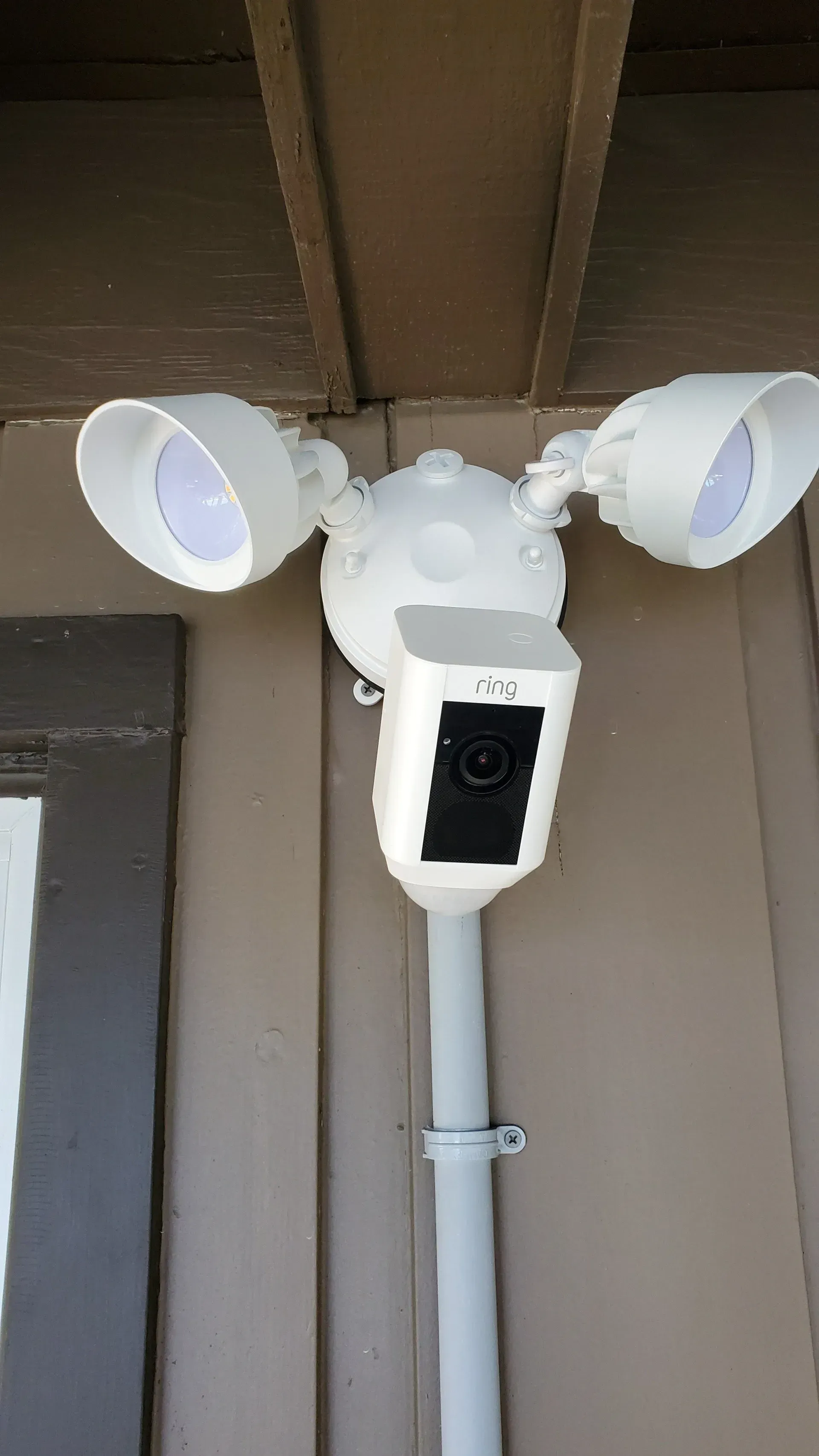 A security camera is mounted on a pole on the side of a building.