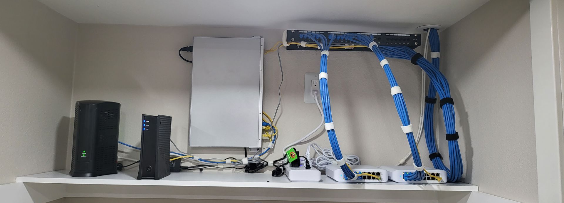 A shelf with a bunch of wires hanging from the ceiling.