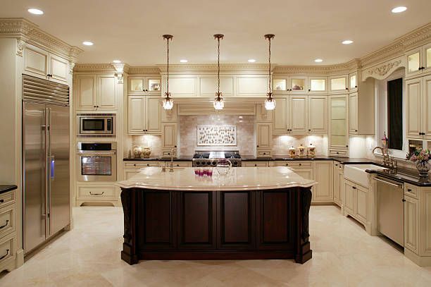 A kitchen with white cabinets and stainless steel appliances and a large island in the middle.