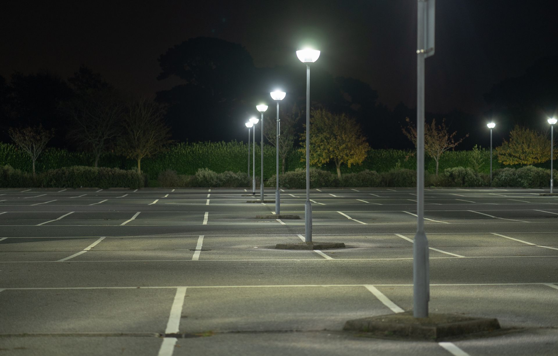 An empty parking lot at night with lots of street lights.