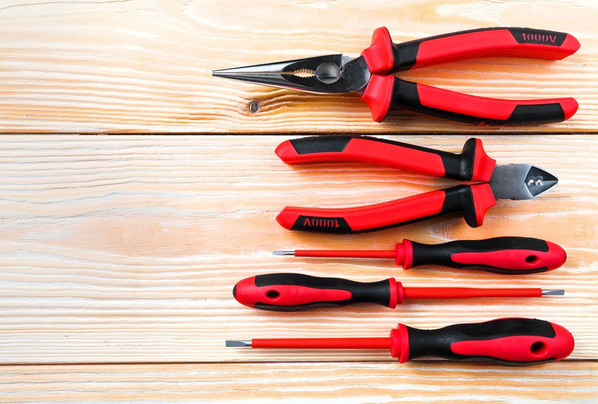 A set of pliers and screwdrivers on a wooden table.