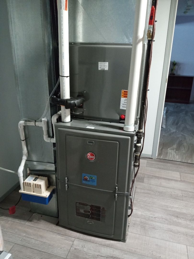 Furnace unit against a wall, featuring ductwork, vents, and a control panel.