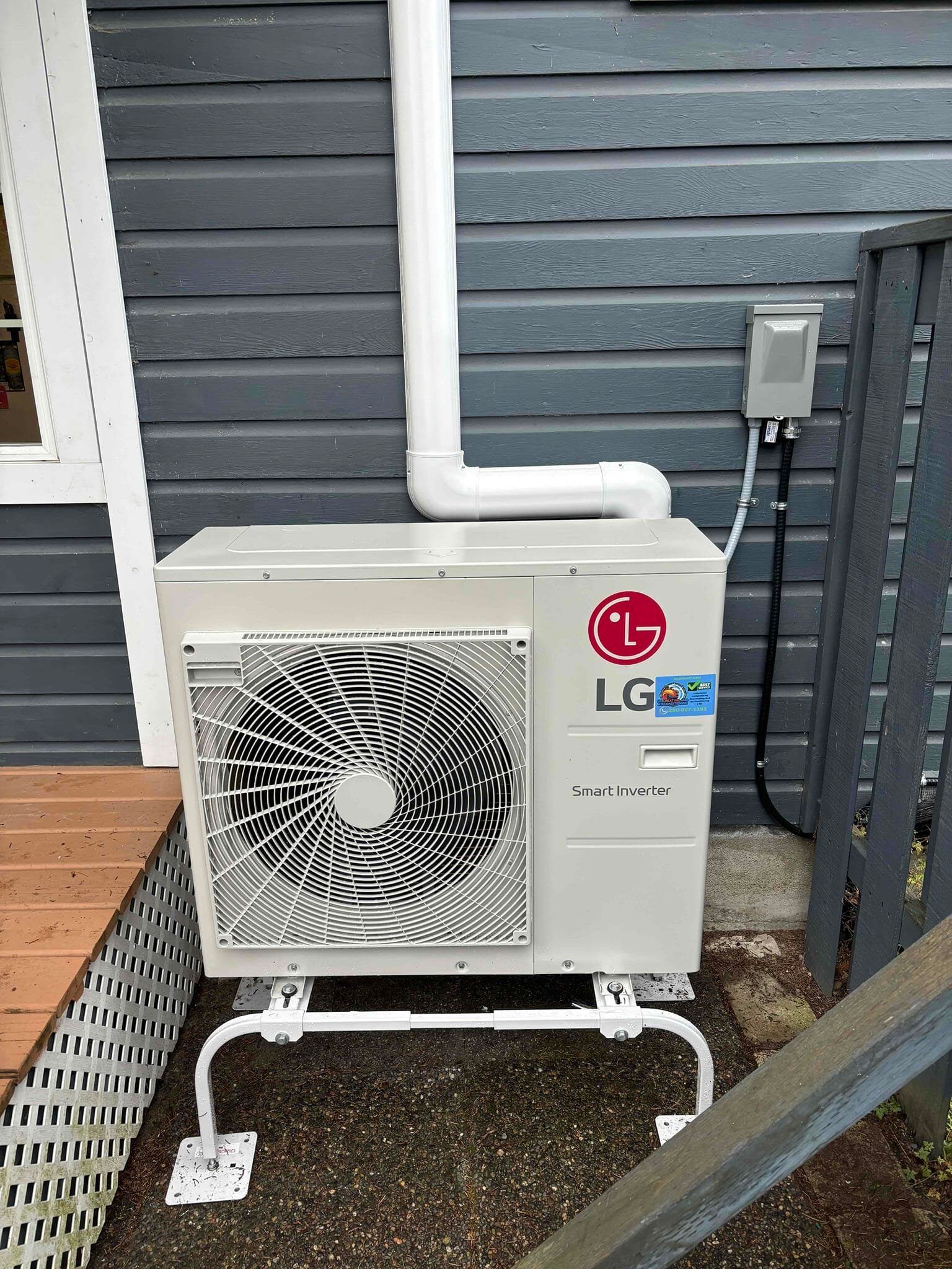 An lg air conditioner is installed on the side of a house.