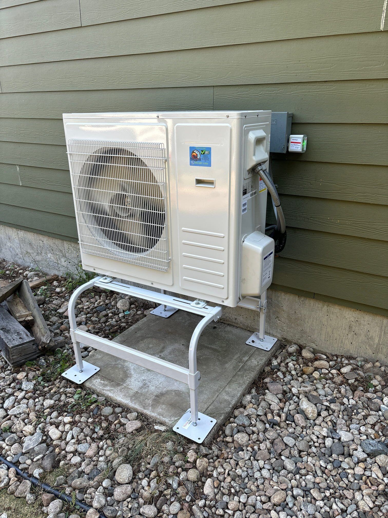 A white air conditioner is sitting on a stand outside of a house.