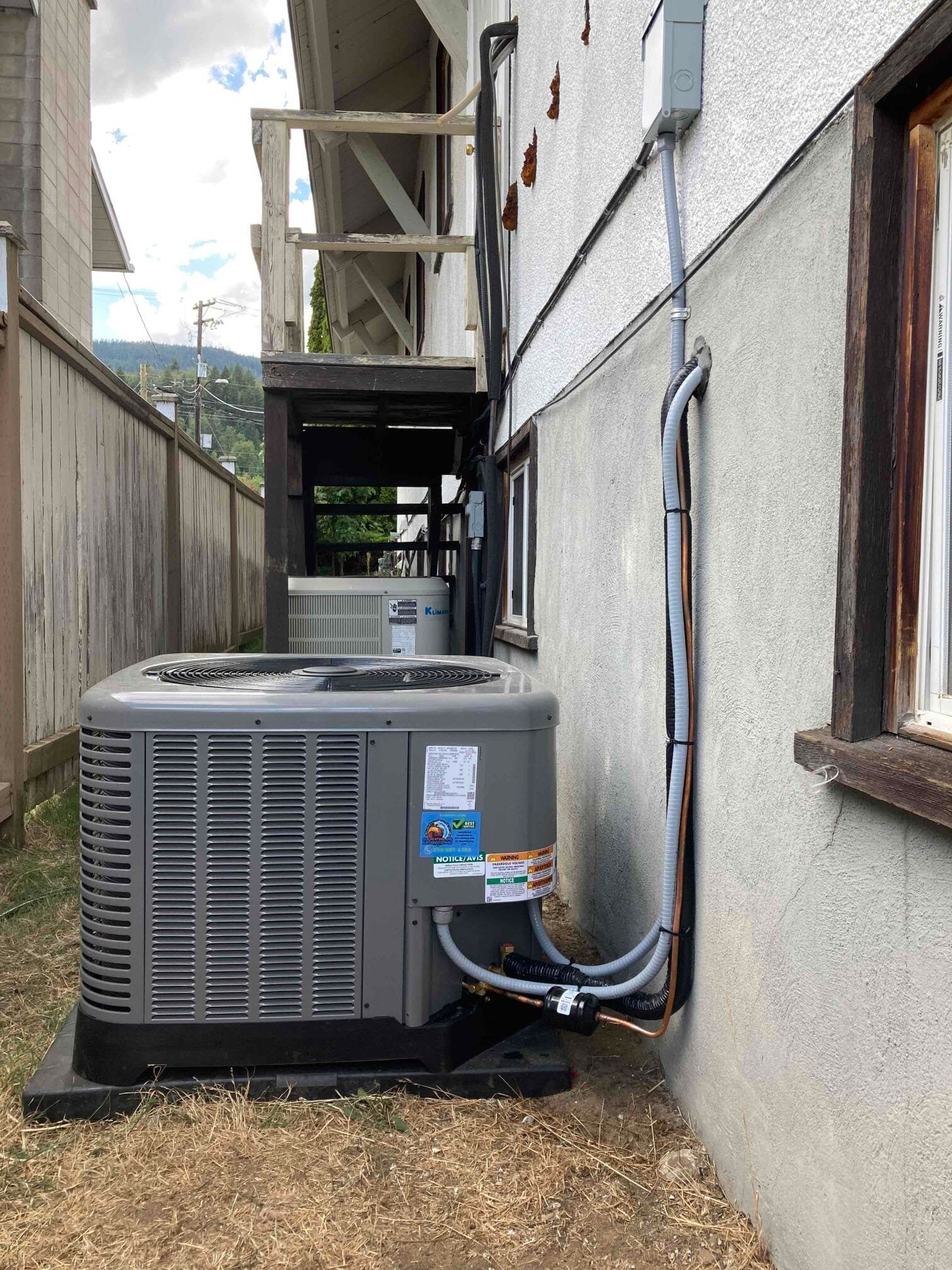 A large air conditioner is sitting on the side of a building next to a window.