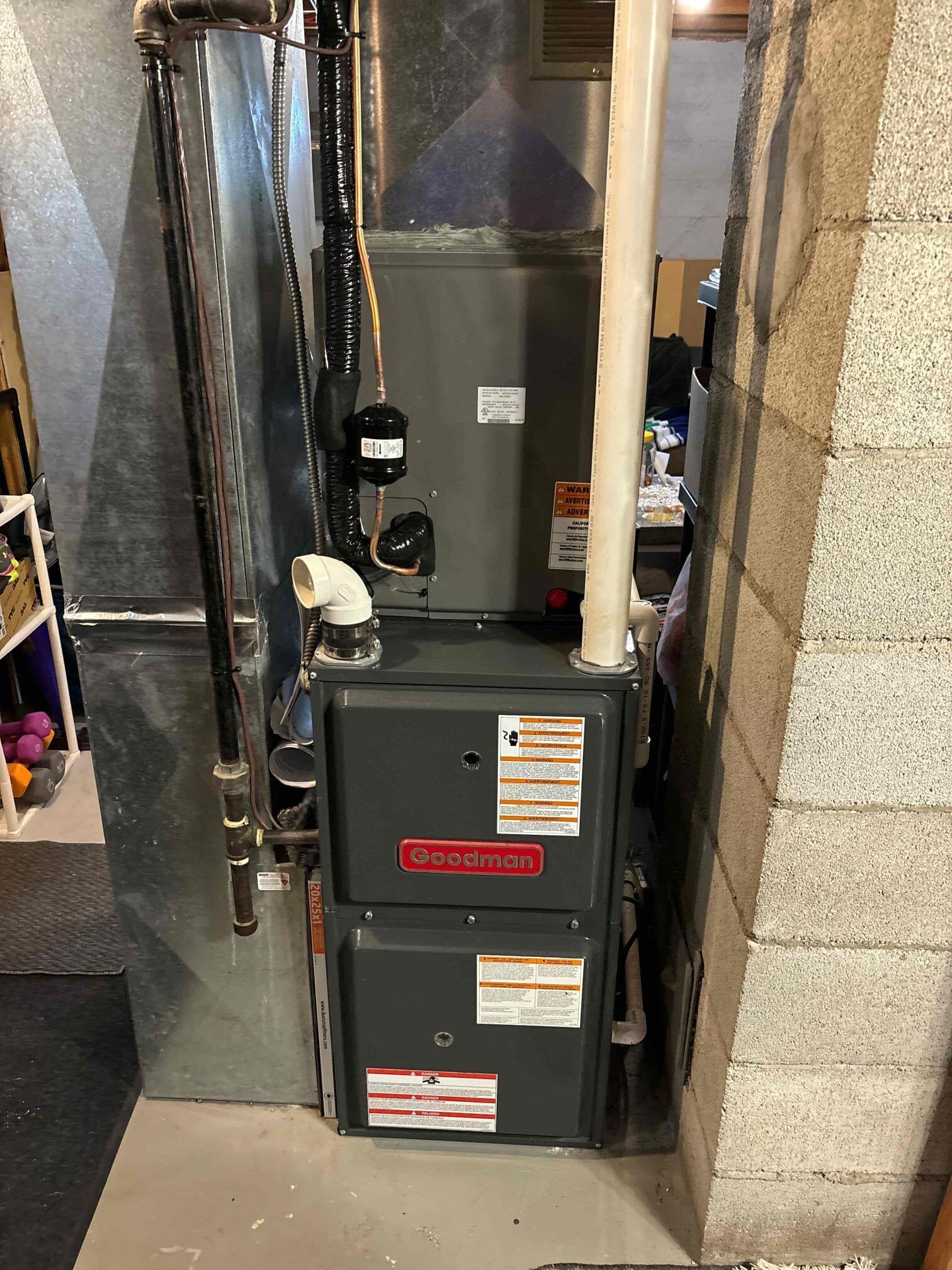 A furnace is sitting in a basement next to a brick wall.