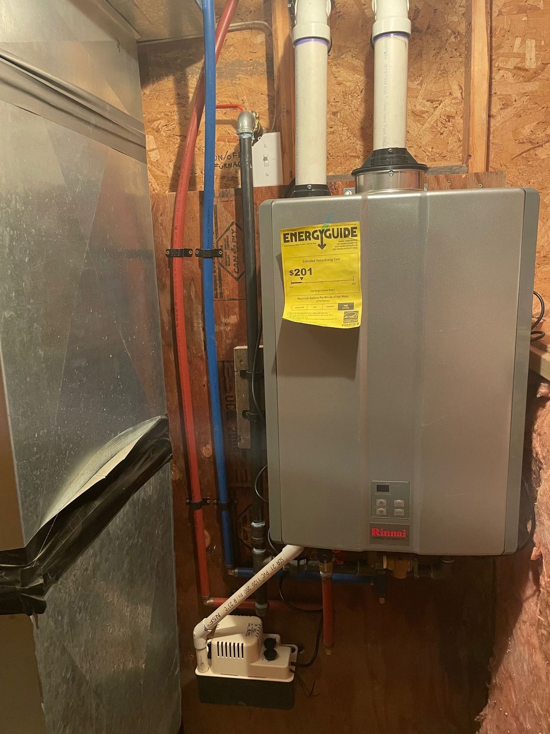 A water heater is installed in a basement next to a refrigerator.