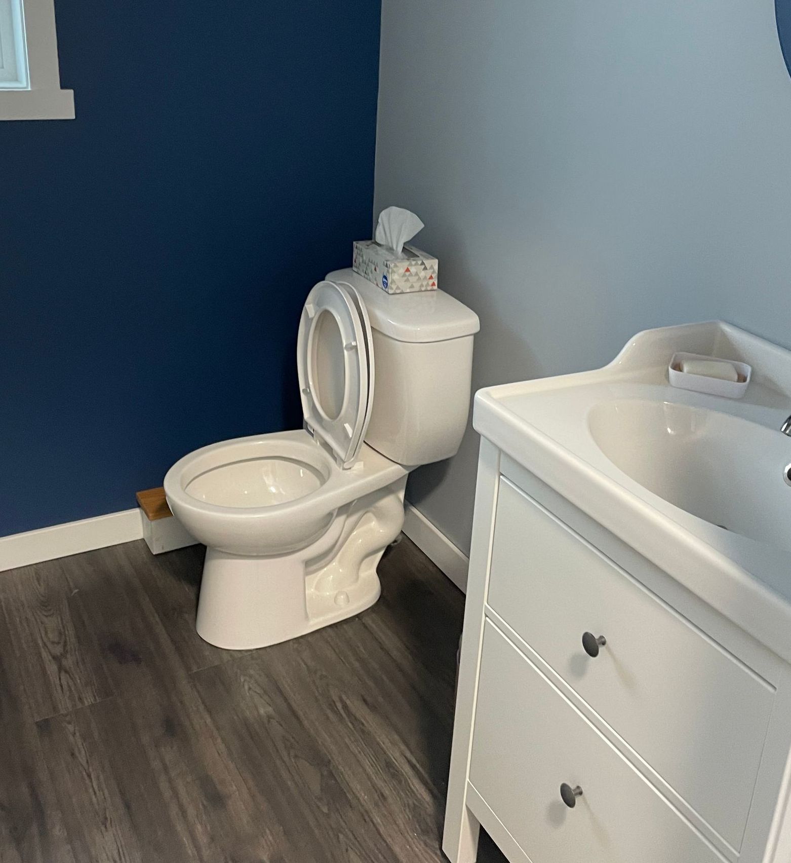 A bathroom with a toilet , sink and dresser.
