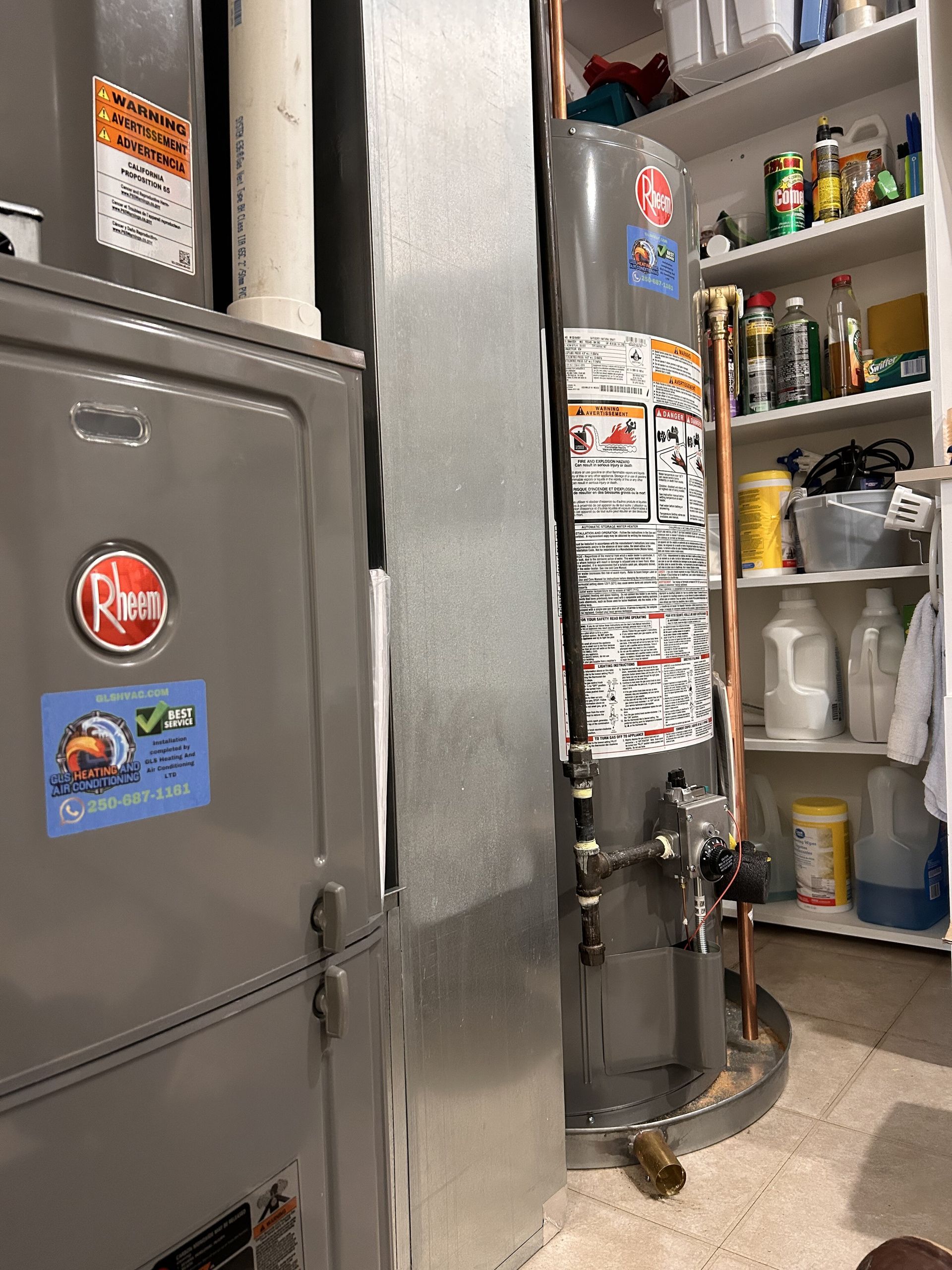 A furnace and water heater are next to a pantry. The furnace is silver, and the water heater is blue.