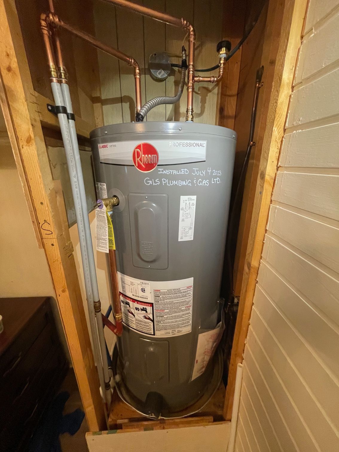 A water heater is sitting in a corner of a room.