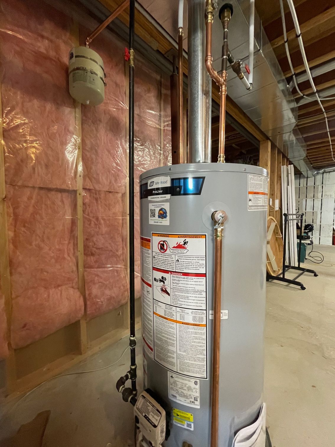 A water heater is sitting in a room under construction.