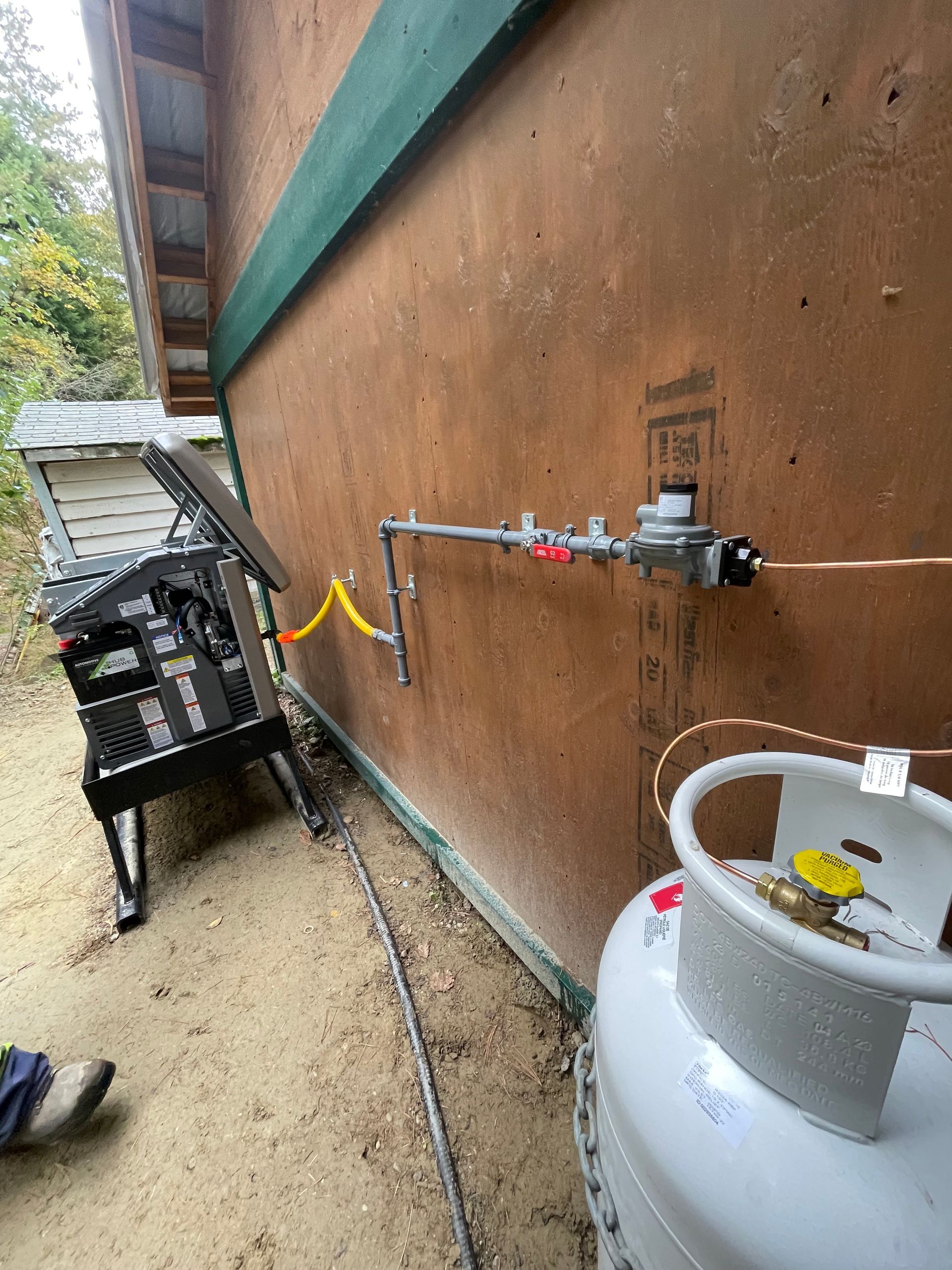 A propane tank is attached to a wall next to a hose.