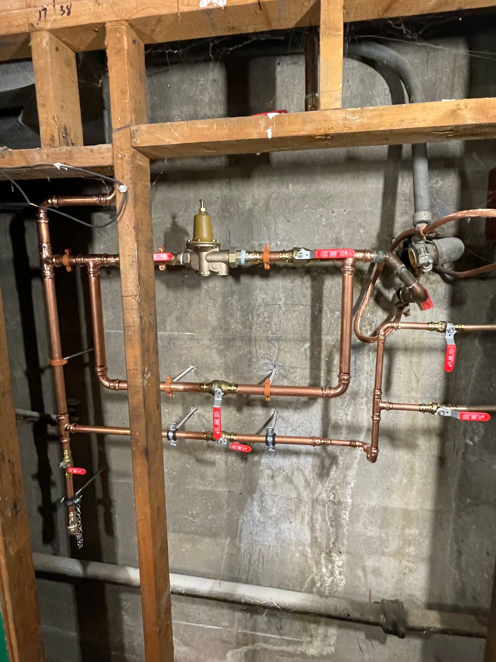 A bunch of copper pipes are hanging on a wall.
