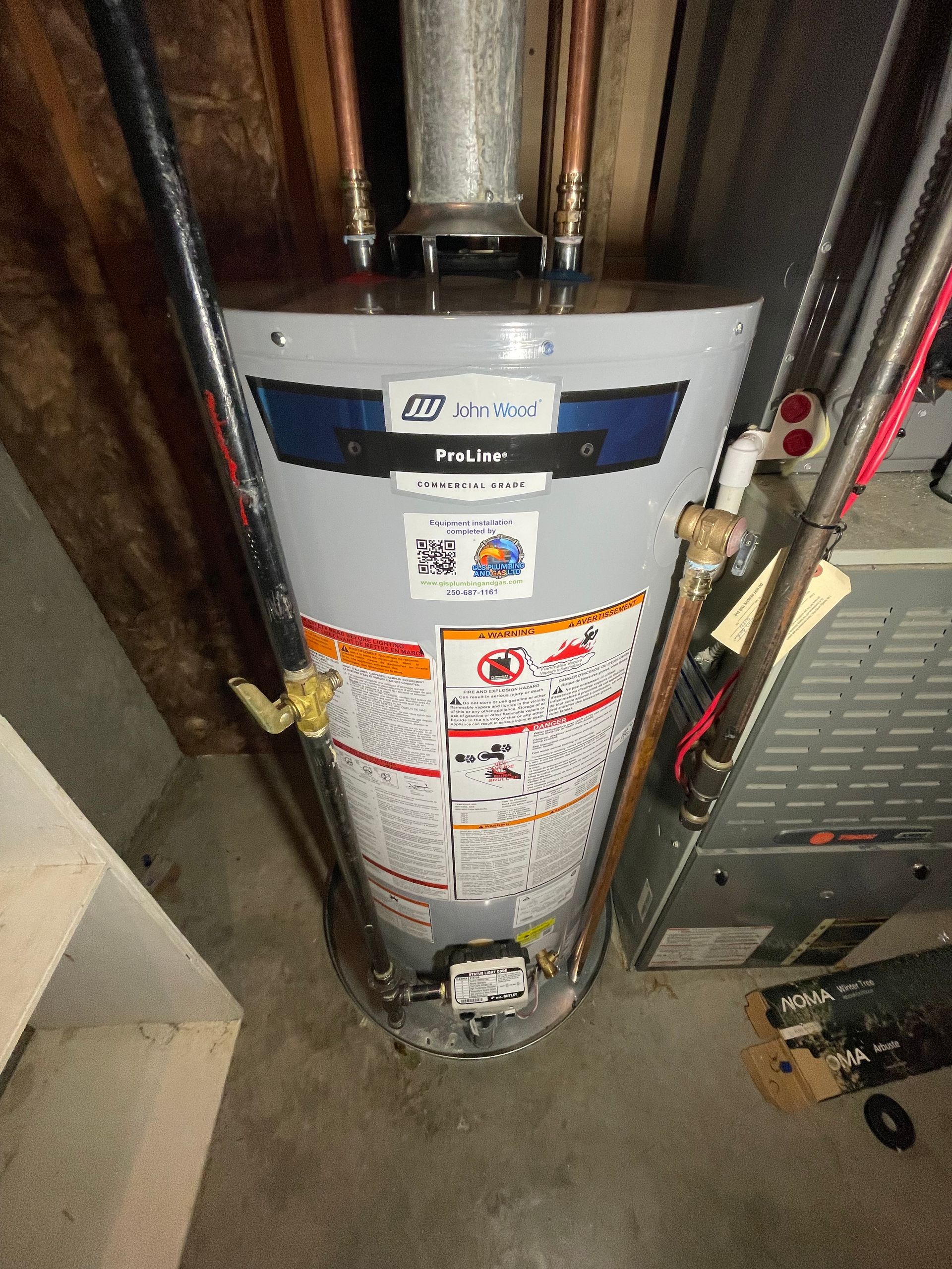 A water heater is sitting in a basement next to a furnace.