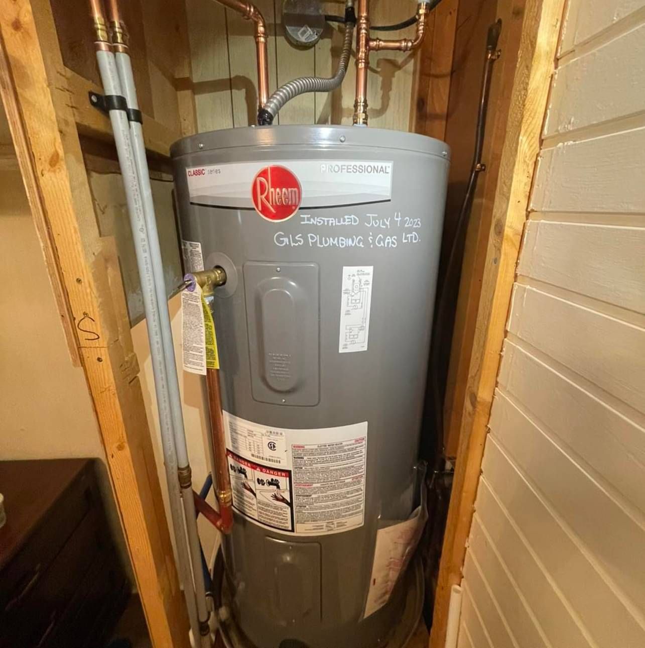 A gray water heater is sitting in a corner of a room.