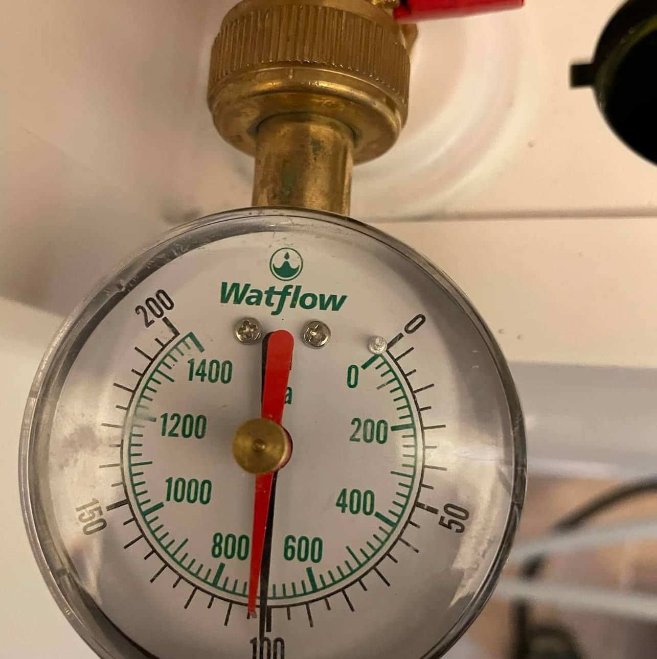 A watflow gauge is hanging from a brass pipe