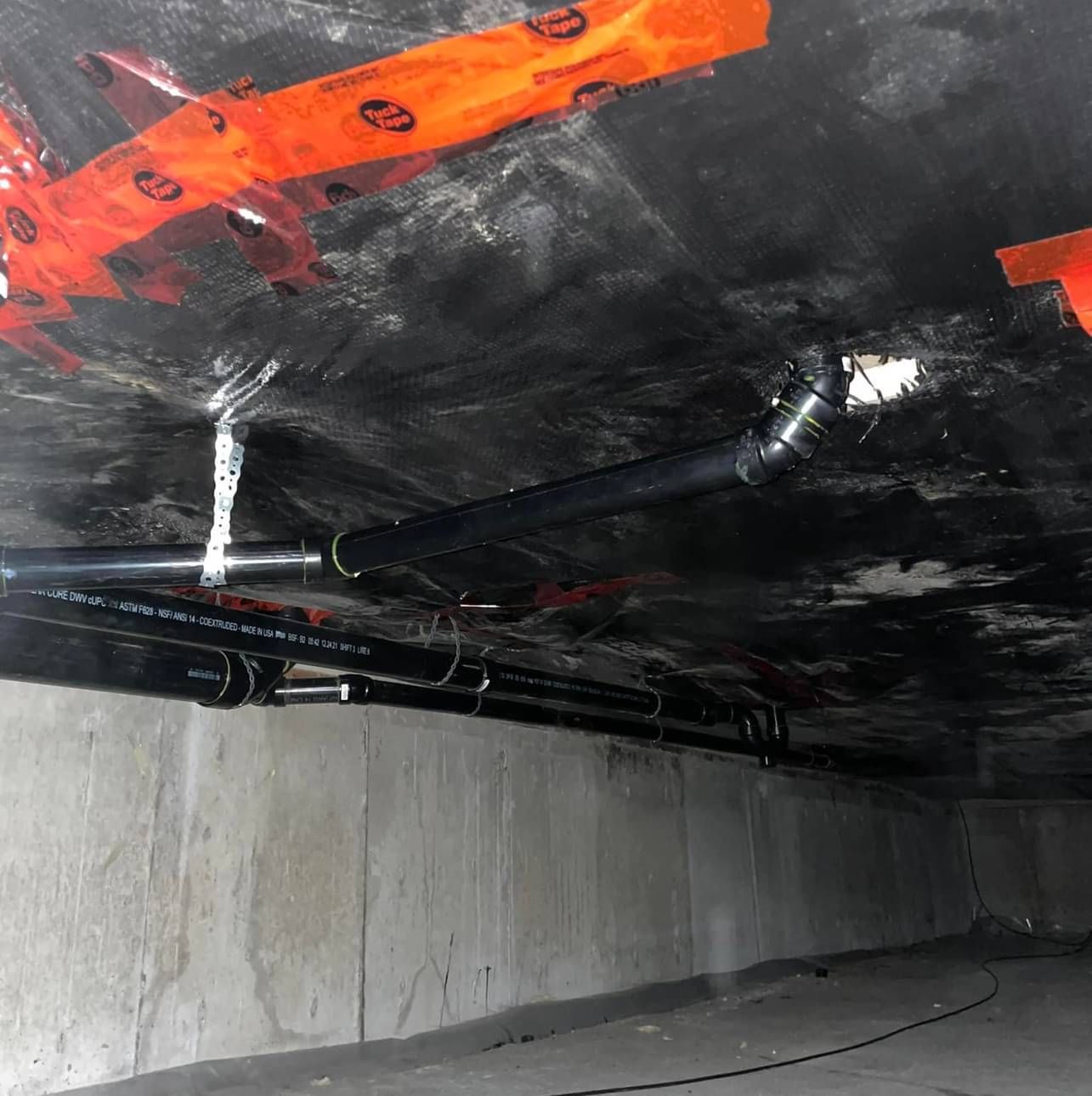 Black pipes are hanging from the ceiling in a dark room