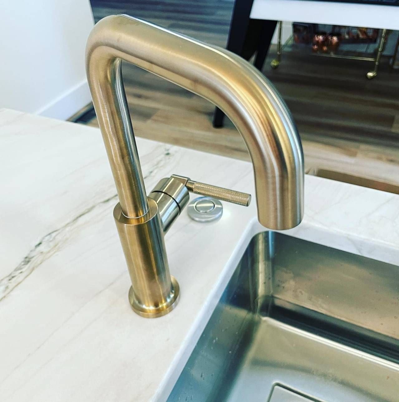 A kitchen sink with a brass faucet on top of it