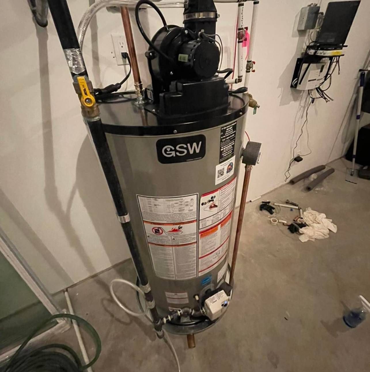 A gsw water heater is sitting on the floor in a room.