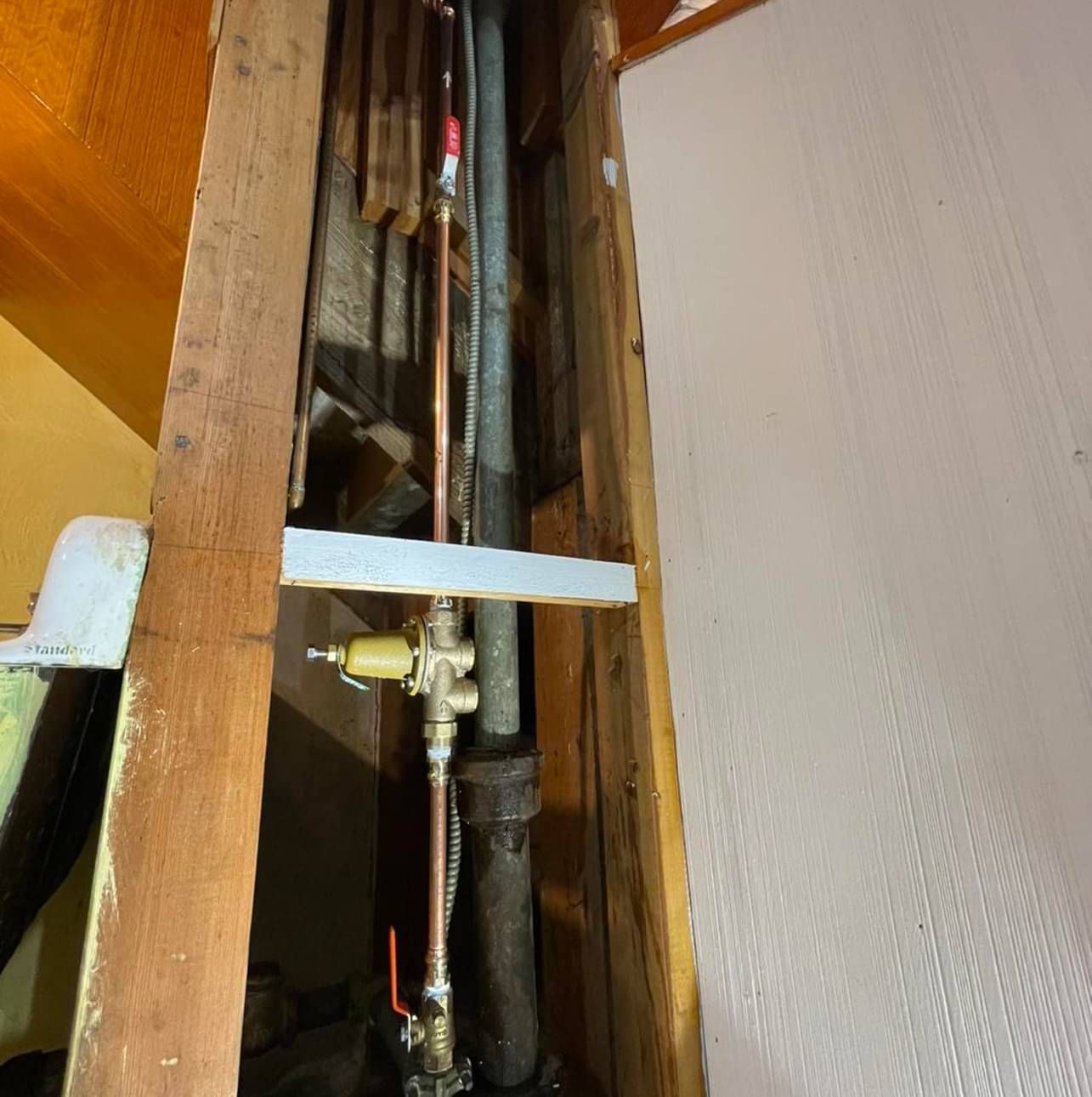 A close up of a pipe in a wooden wall.