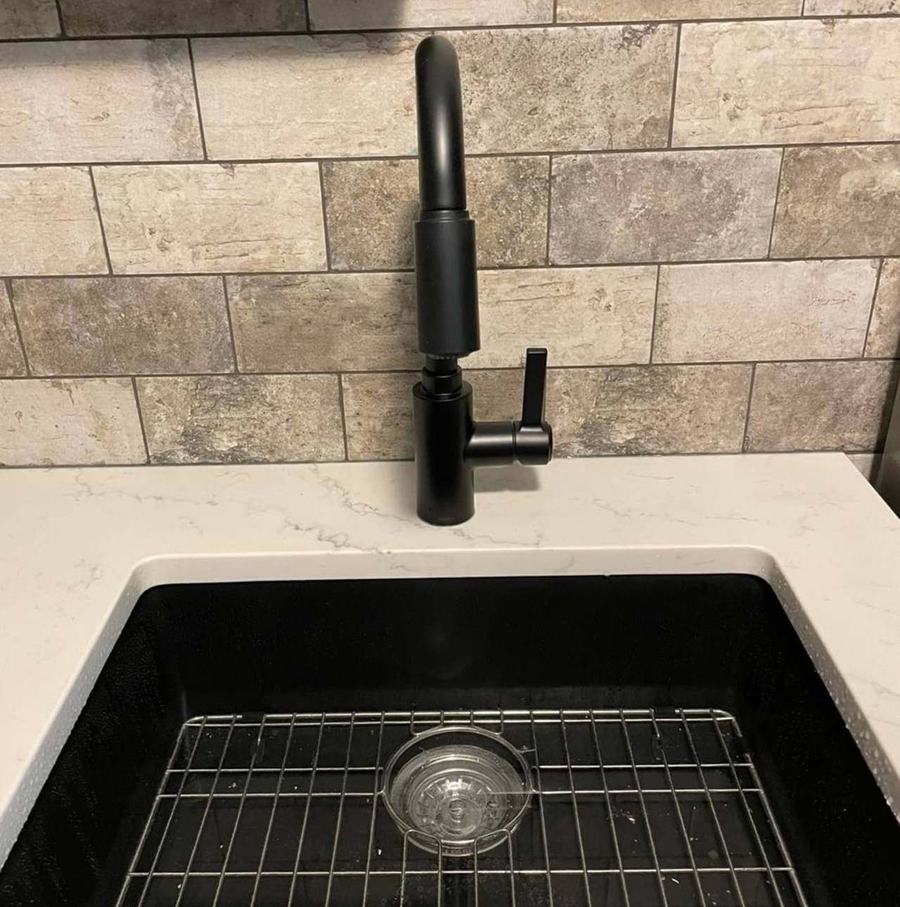A kitchen sink with a black faucet and drain