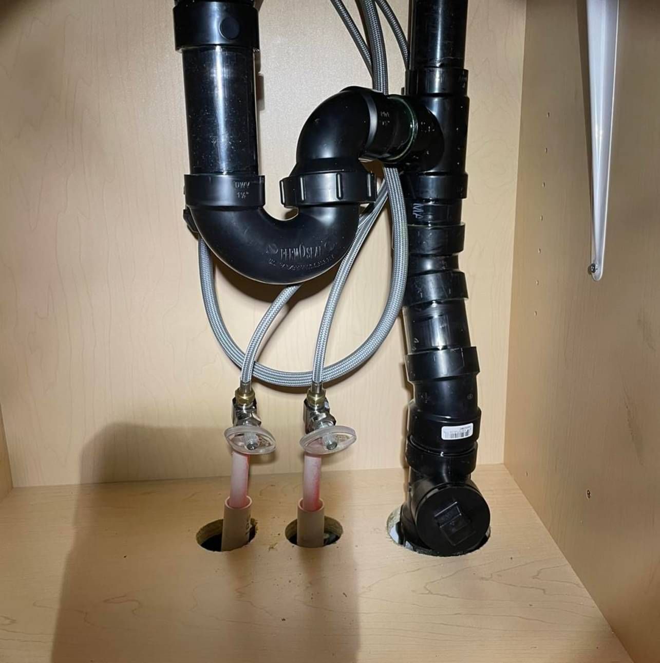 A close up of a drain pipe in a cabinet