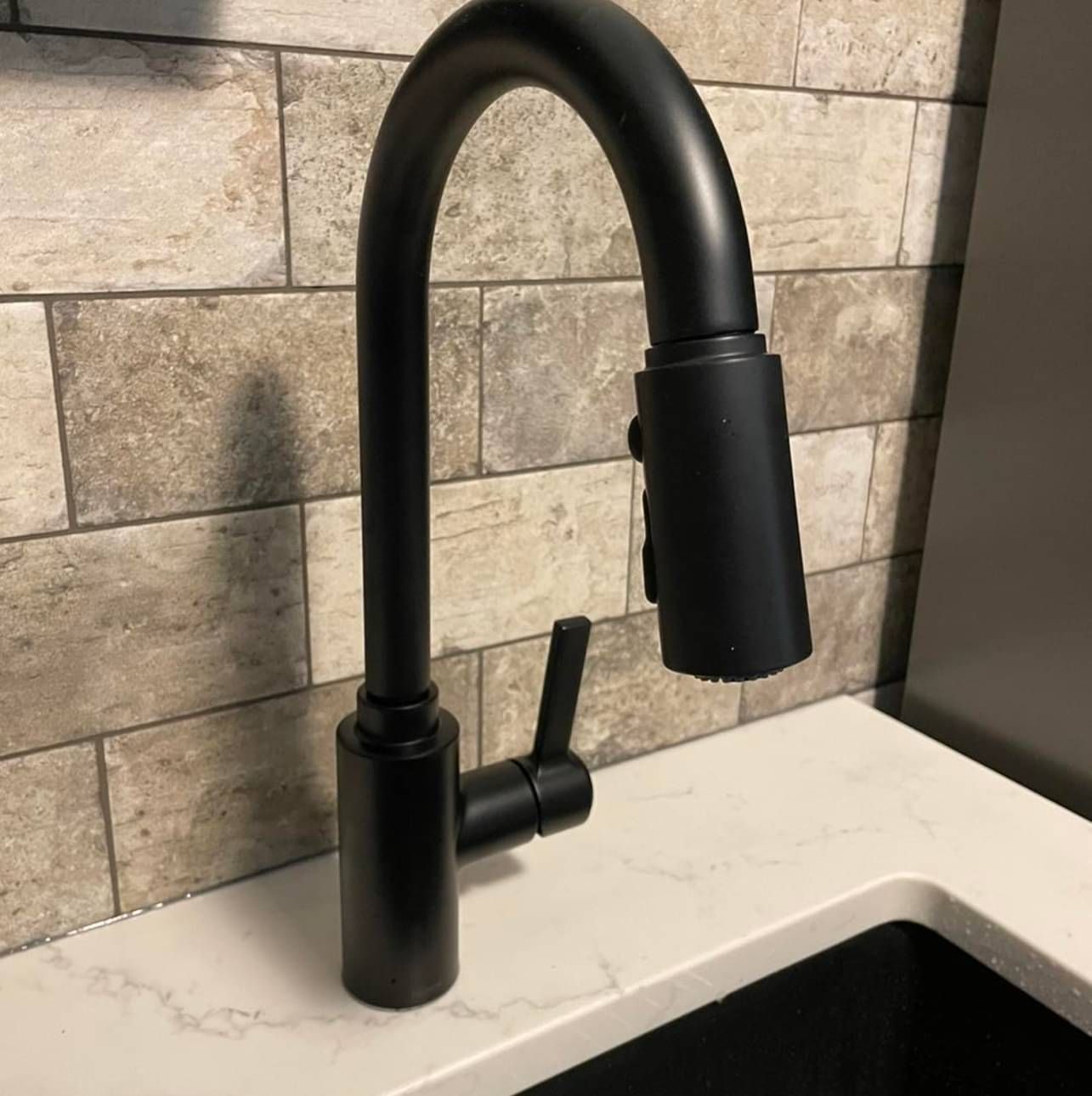 A black faucet is sitting on a counter next to a sink