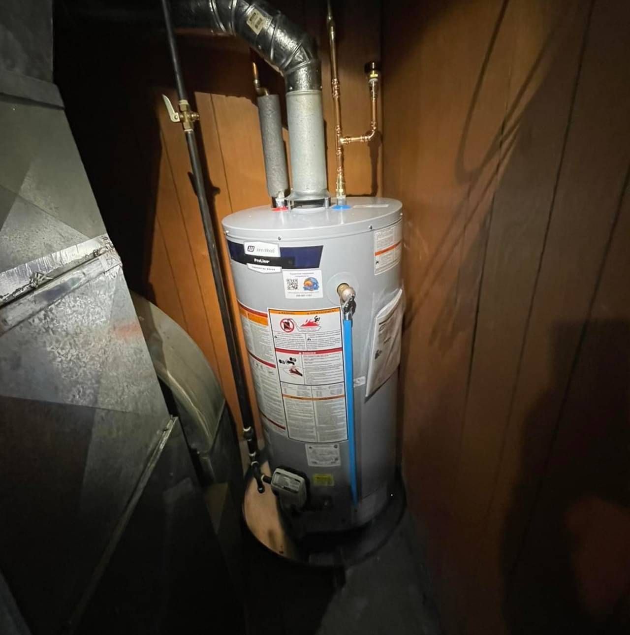A water heater is sitting in a corner of a room