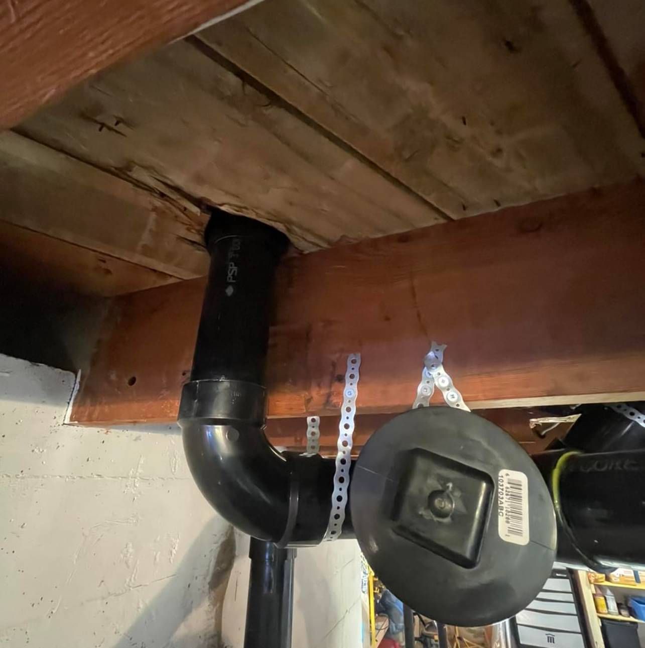 A black pipe is hanging from a wooden ceiling.