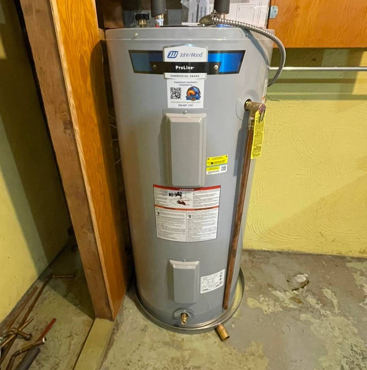 A gray water heater is sitting in a corner of a room.