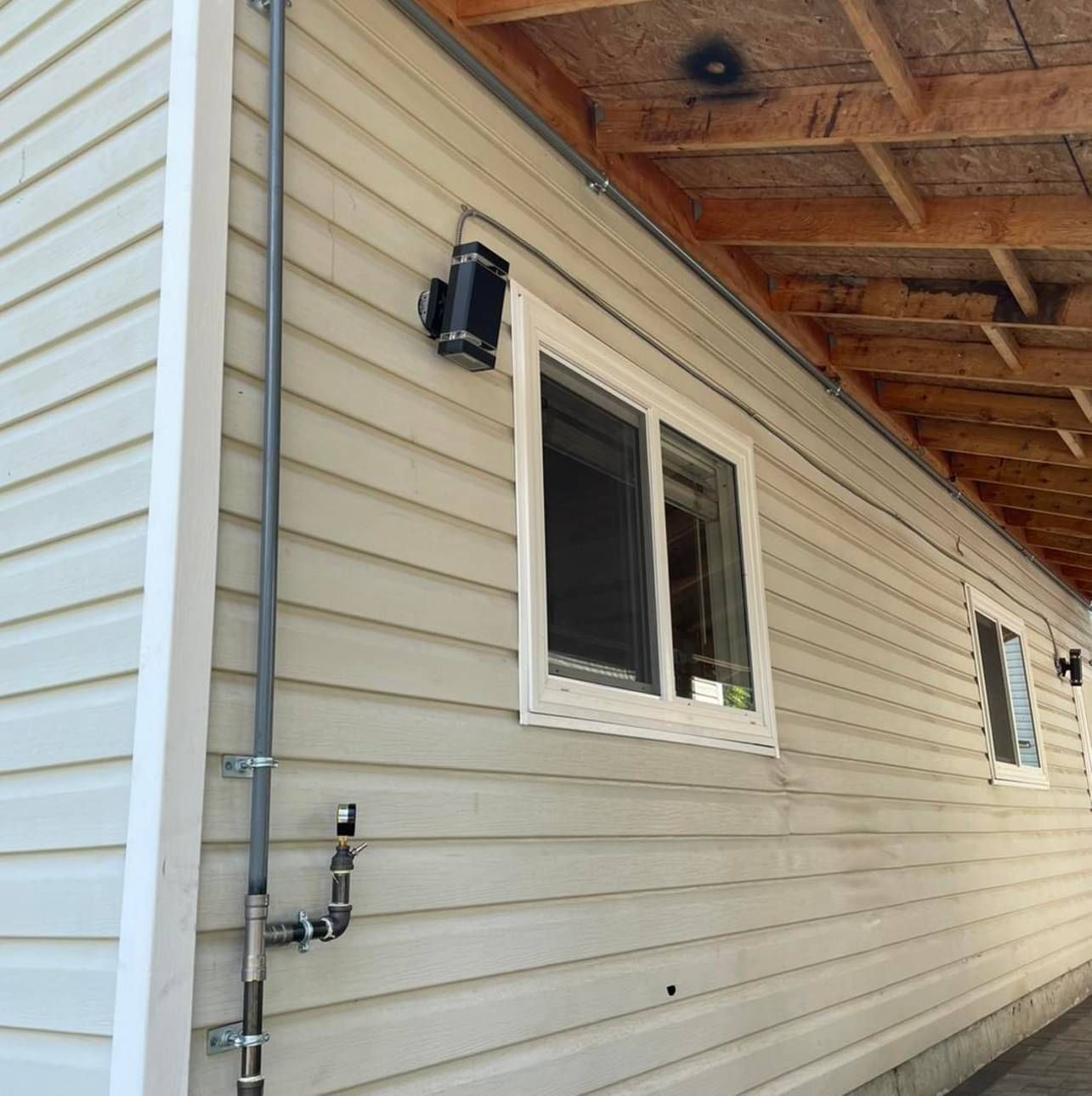 The side of a house with a window and a pipe