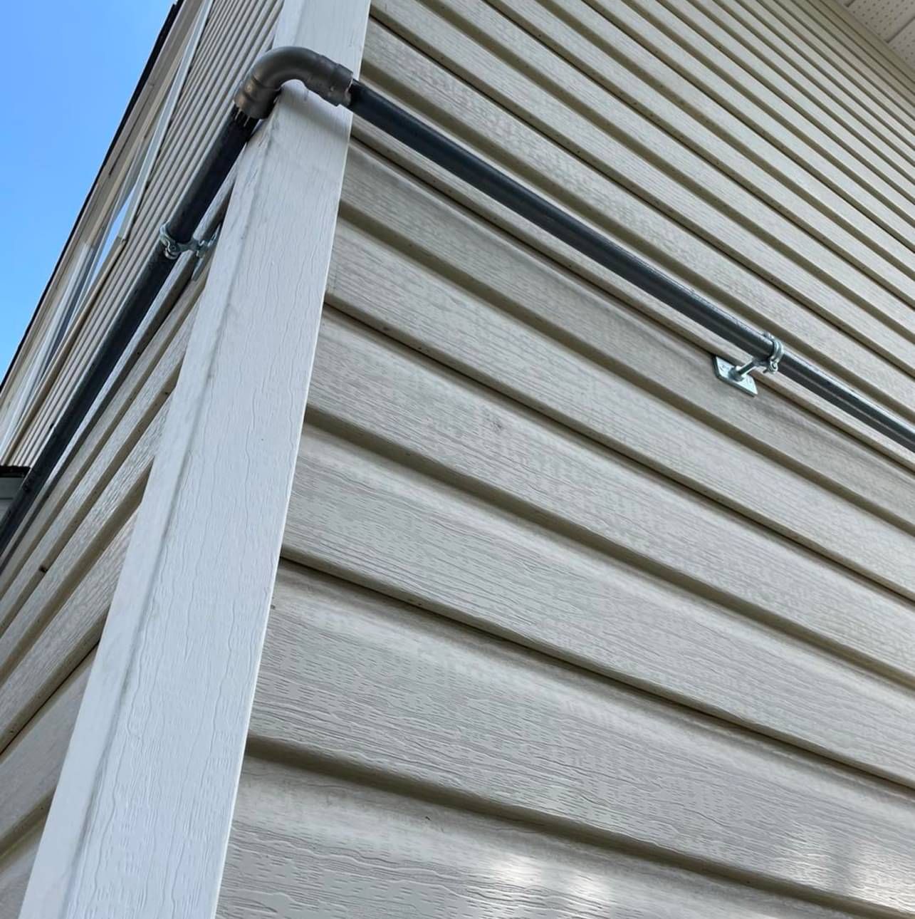 A black pipe is attached to the side of a house.