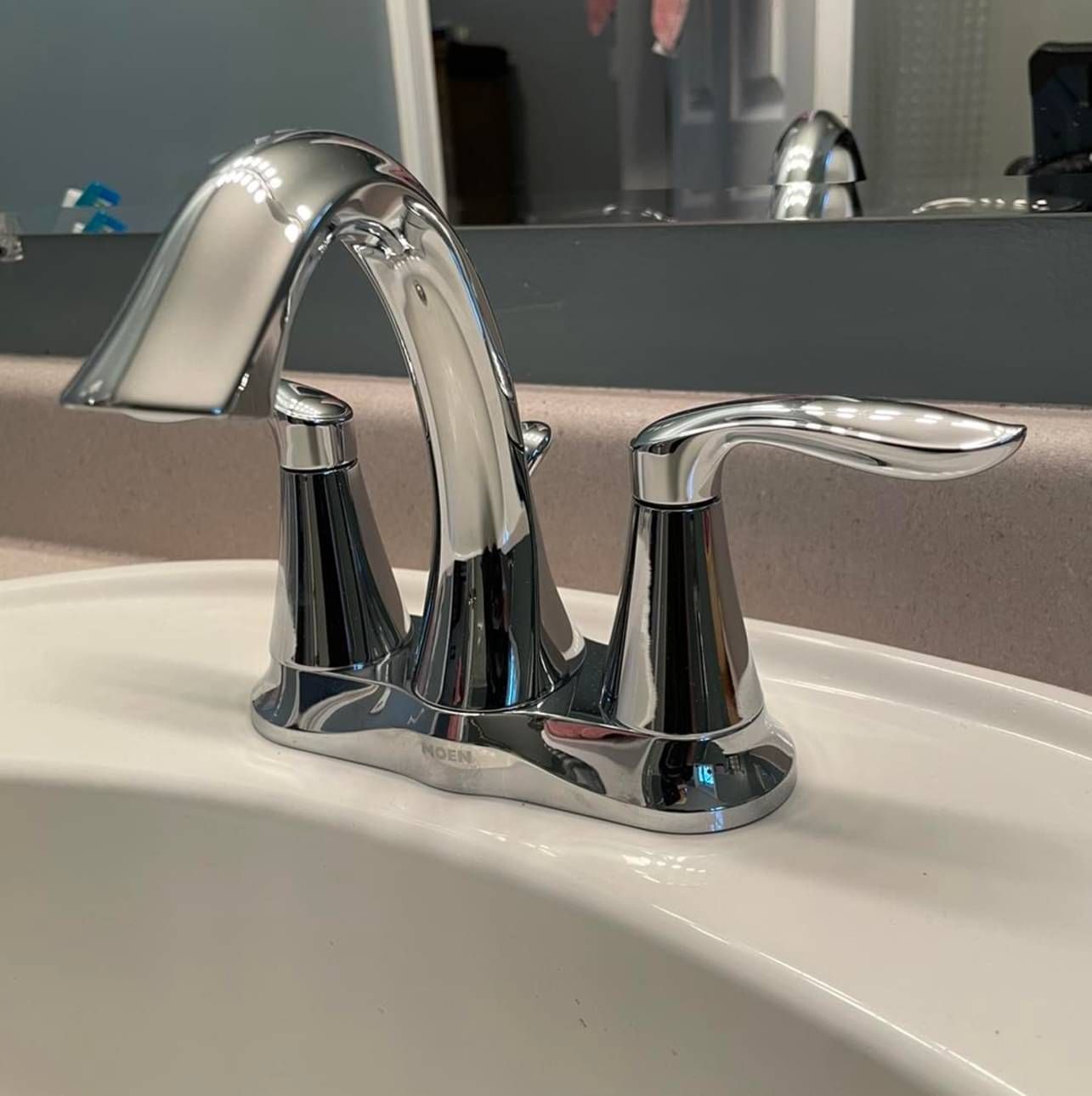 A bathroom sink with a chrome faucet and a mirror in the background.