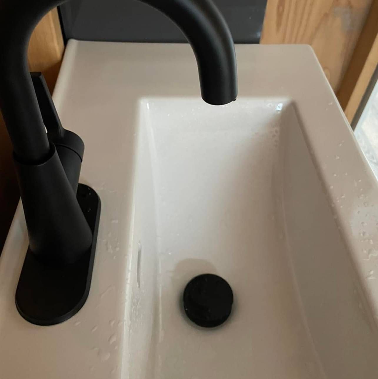 A white sink with a black faucet and a black drain