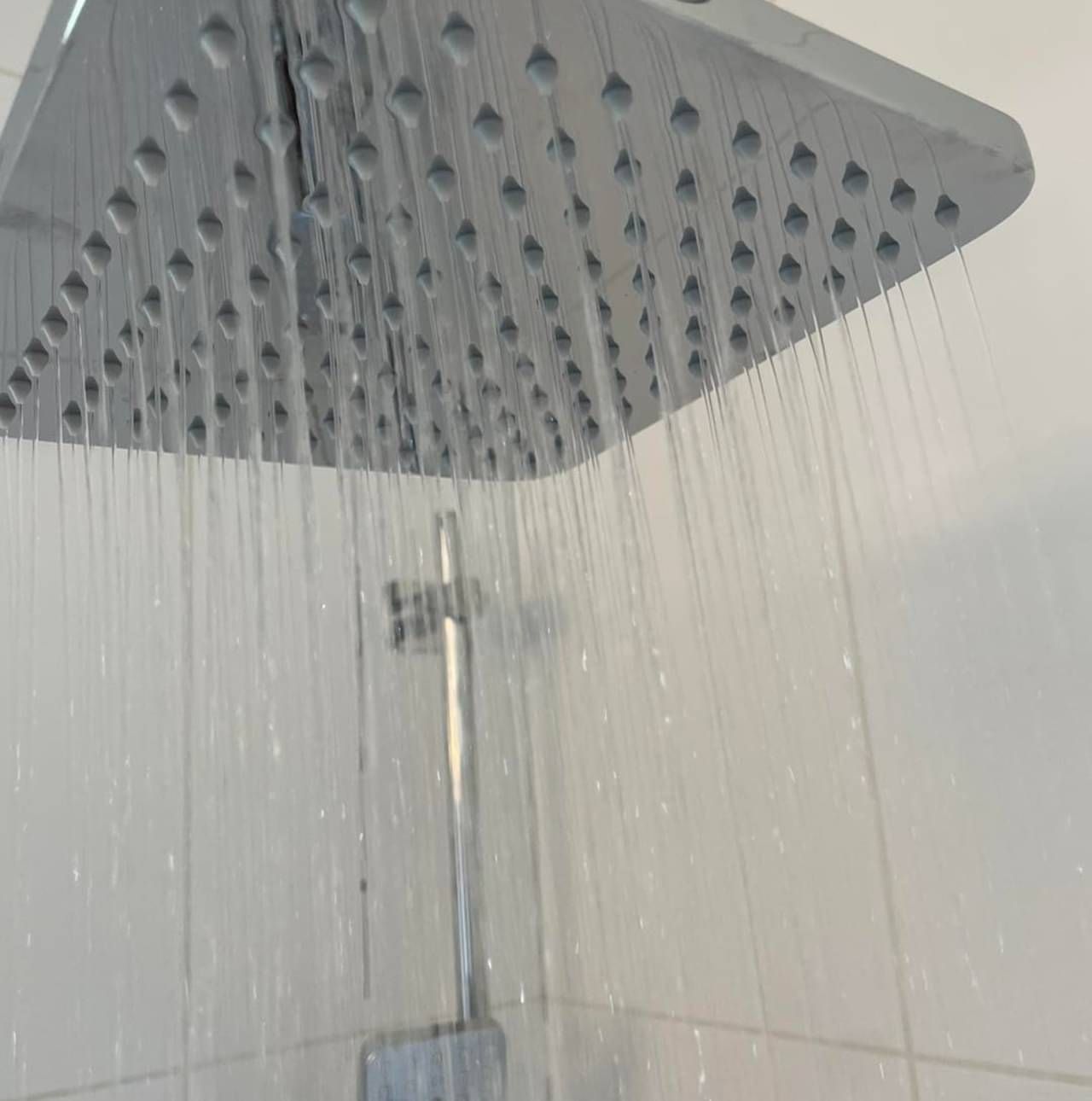 A close up of a shower head with water coming out of it.