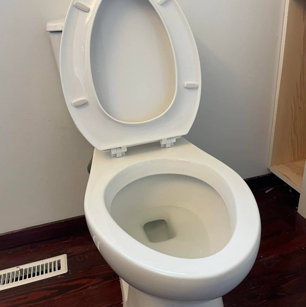 A white toilet with the lid up in a bathroom