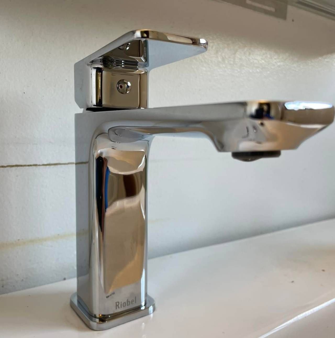 A chrome faucet is sitting on top of a white sink.