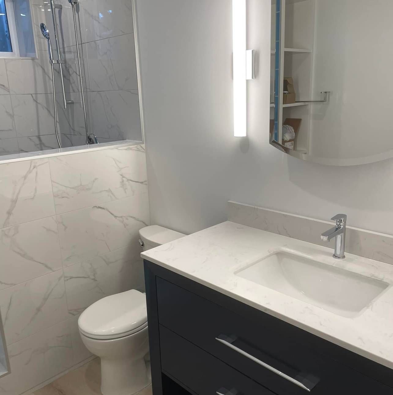 A bathroom with a toilet , sink , mirror and shower.