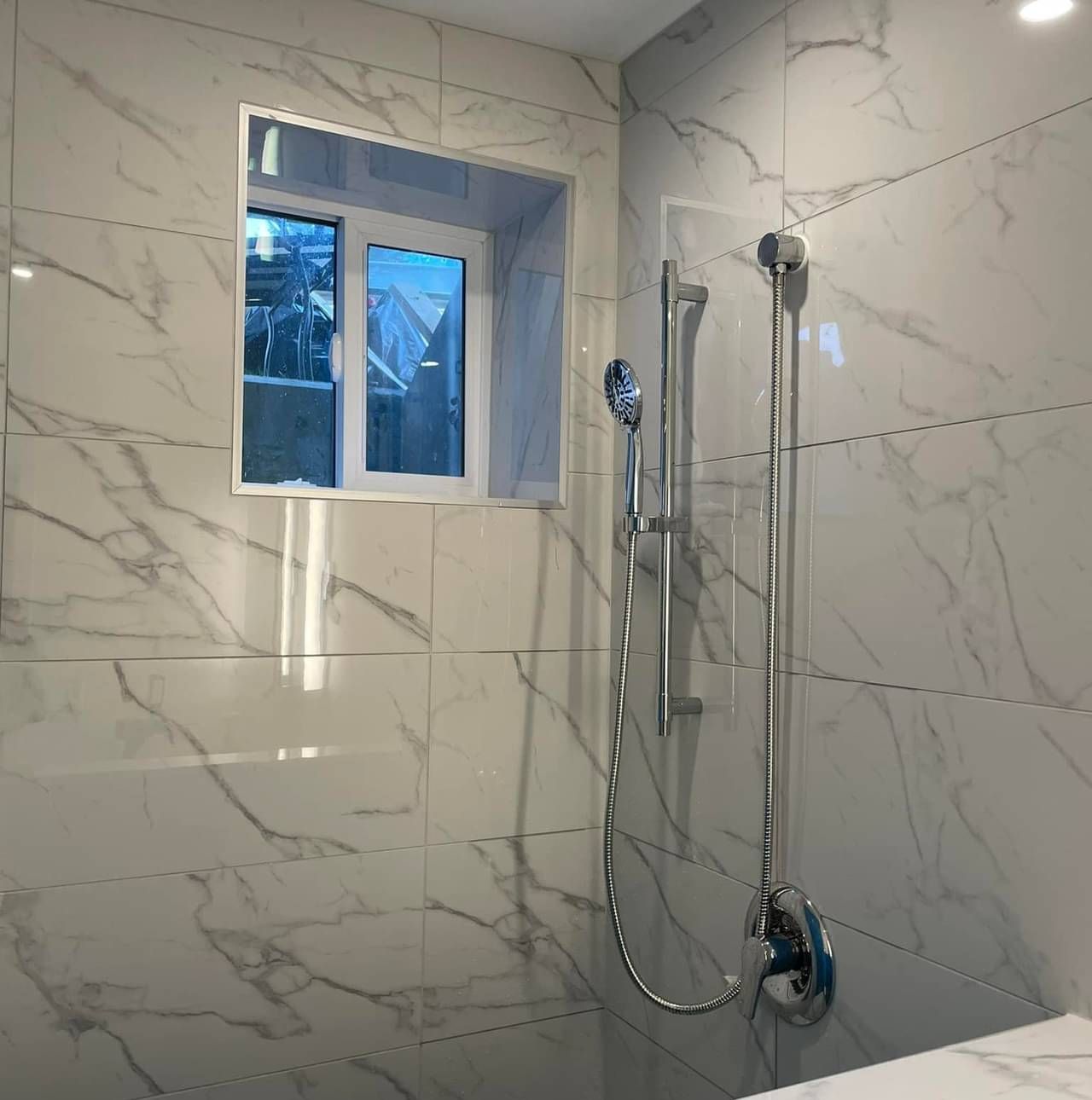 A bathroom with marble tiles and a shower head