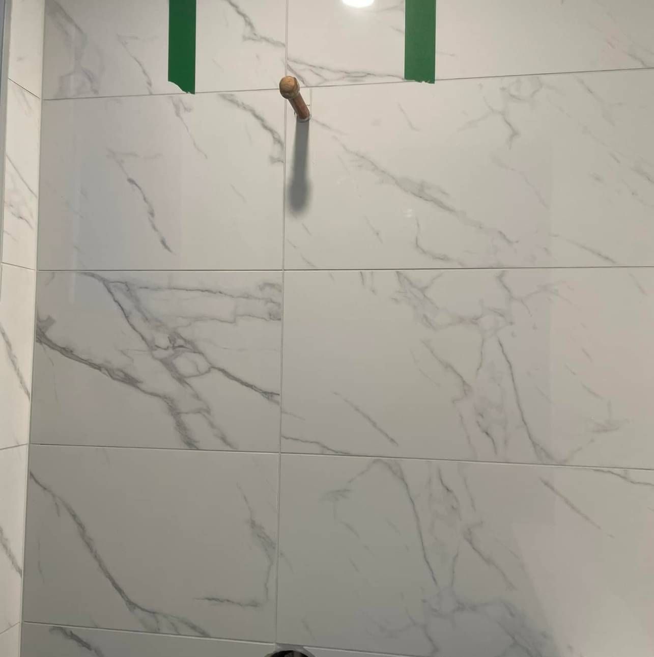 A bathroom with white tiles and green tape on the wall.