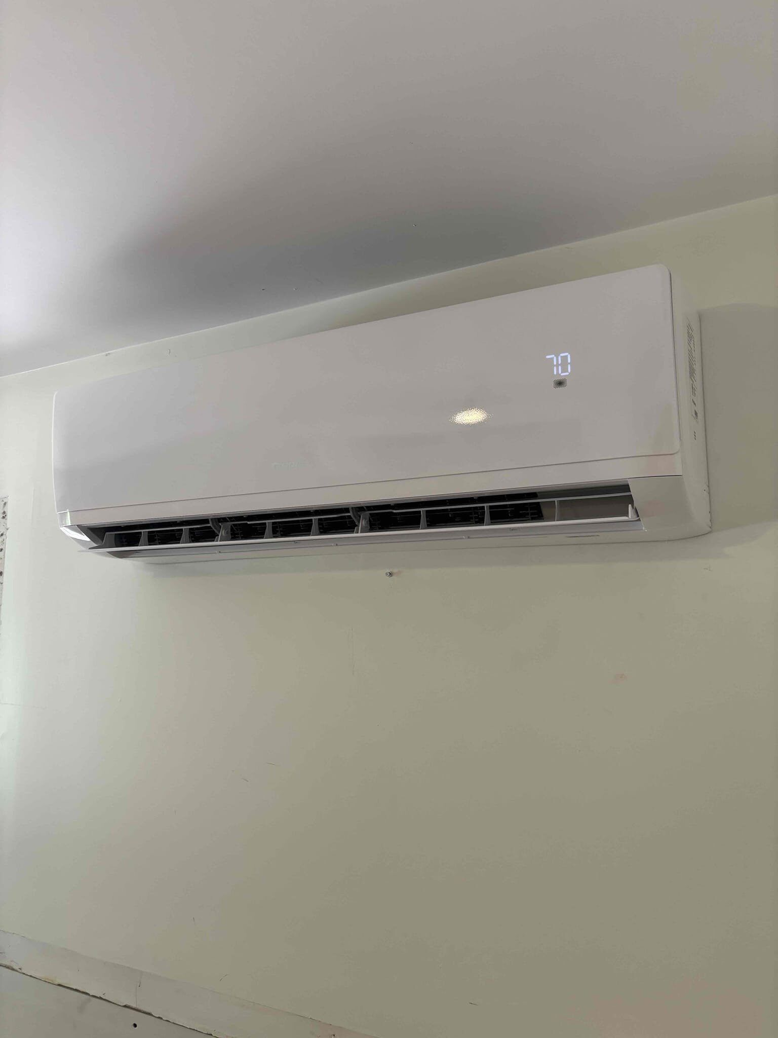 A white air conditioner is hanging on a wall in a room.