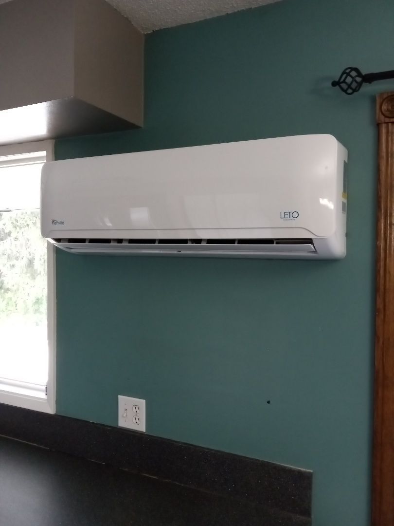 A white air conditioner is hanging on a blue wall in a kitchen.