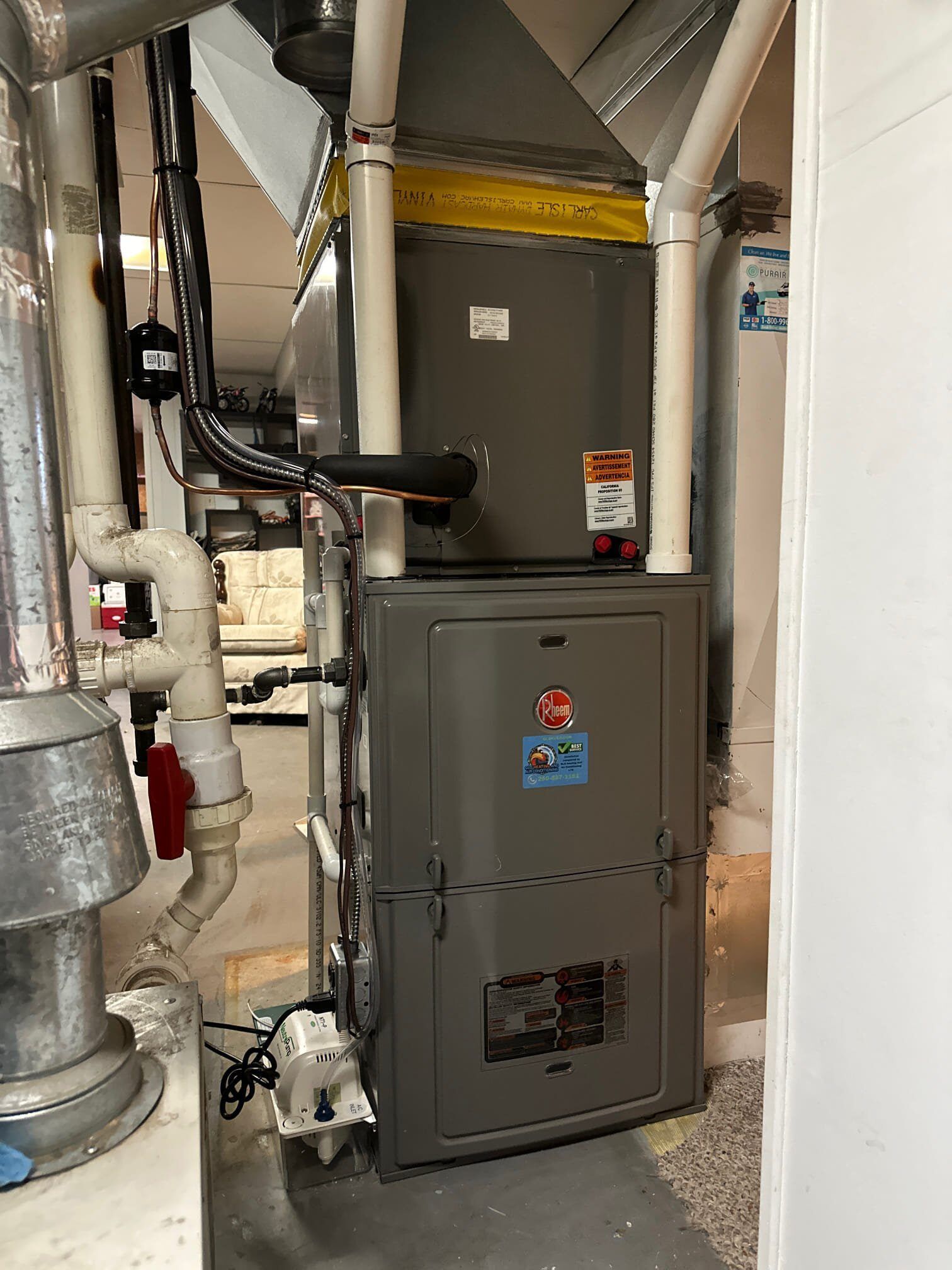 A furnace is sitting in a basement next to a wall.