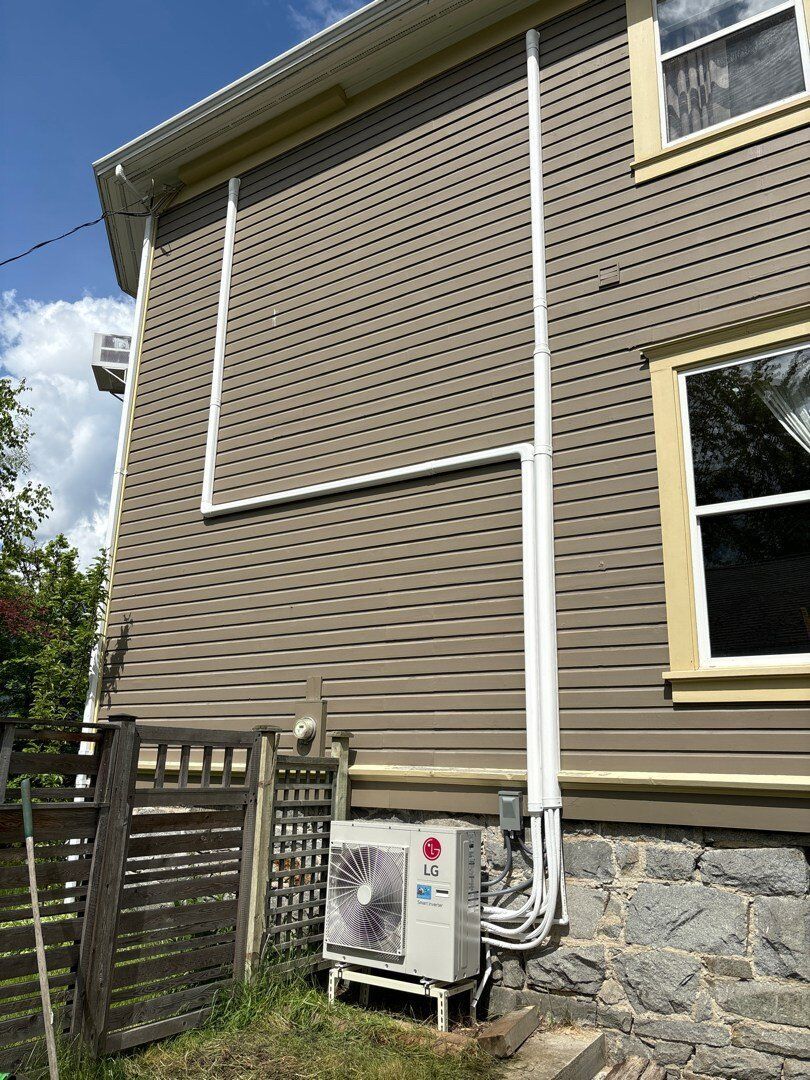 An lg air conditioner is installed on the side of a house.