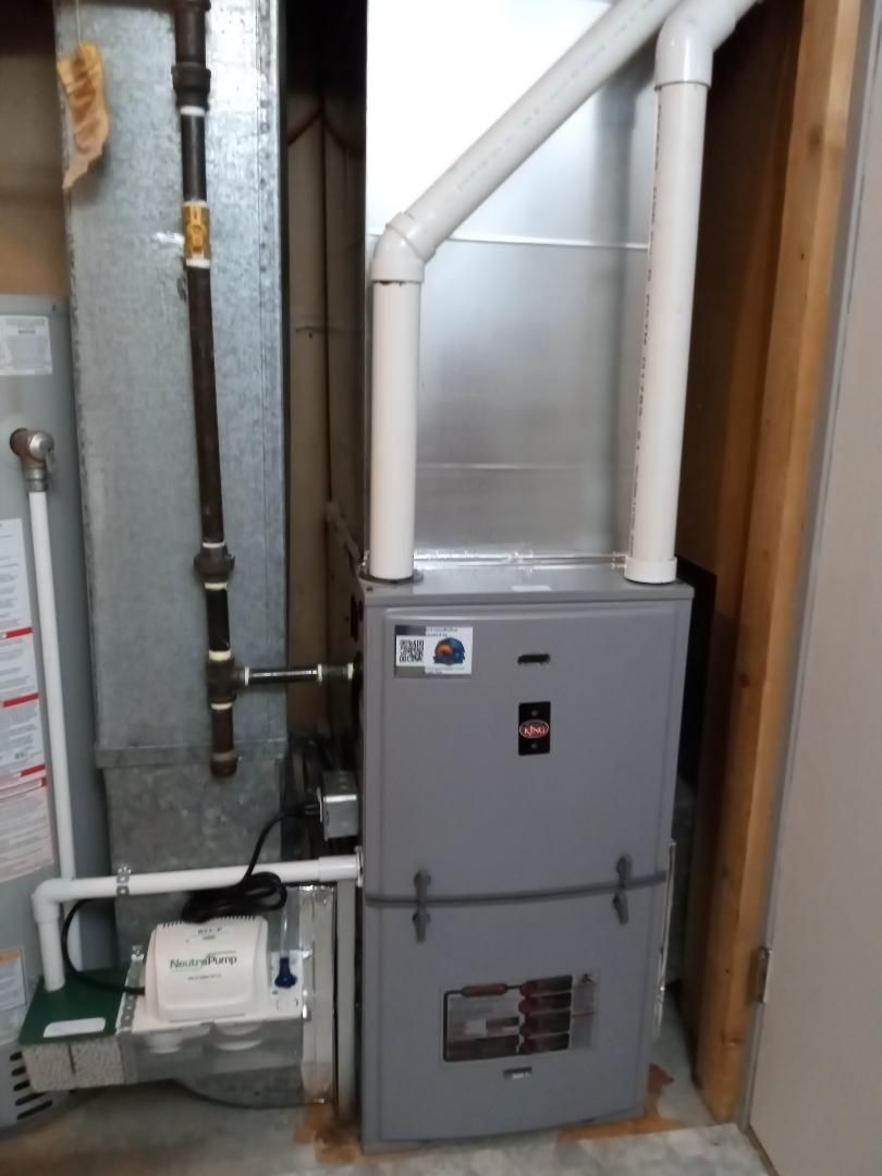 An HVAC system is sitting in a basement next to a door.
