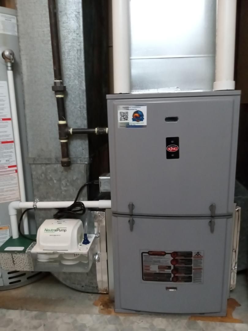 An air conditioner is sitting next to a refrigerator in a basement.