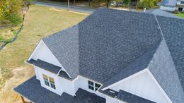 An aerial view of a white house with a black roof.